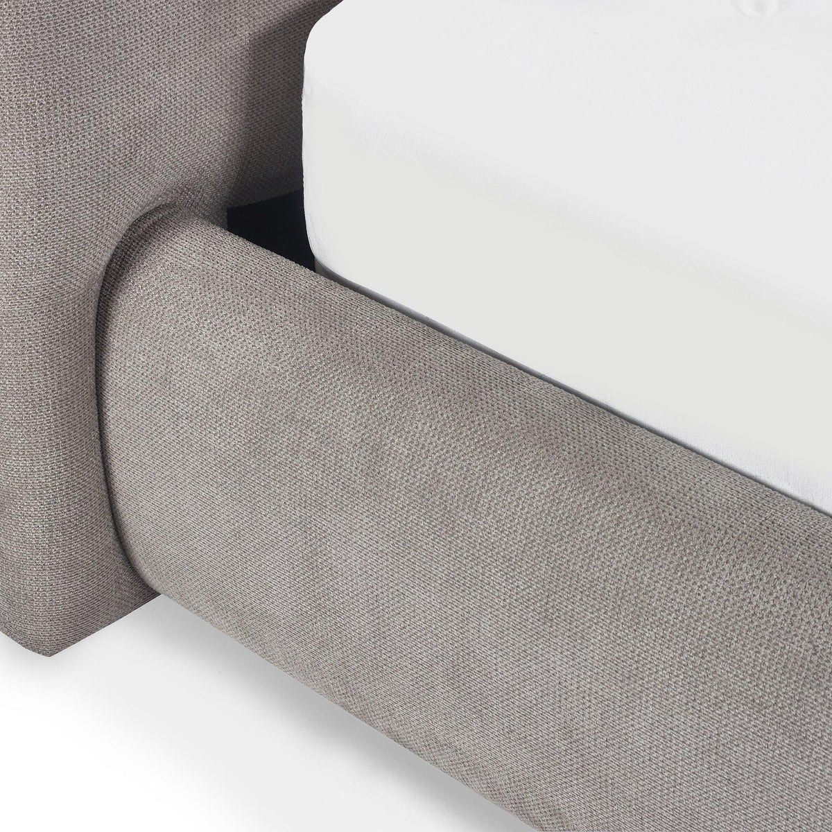 Close-up of grey upholstered bed frame with fabric texture and white mattress corner