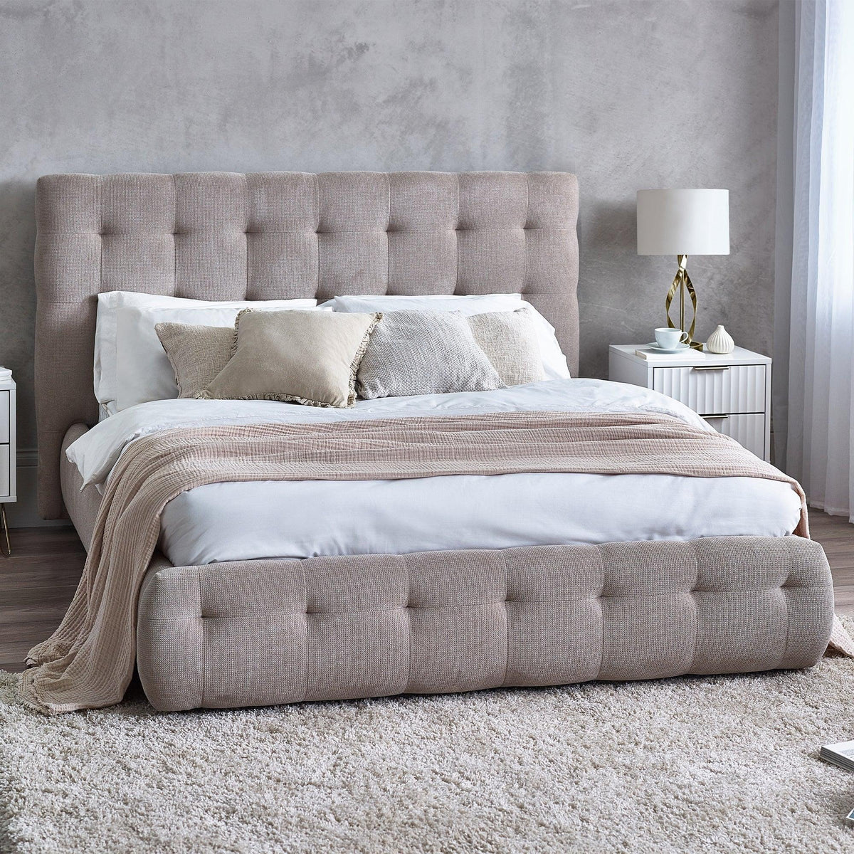 Upholstered bed with tufted headboard in neutral bedroom setting, white bedding and beige throw