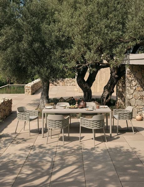 Image of Outdoor dining area with a table and chairs under olive trees.