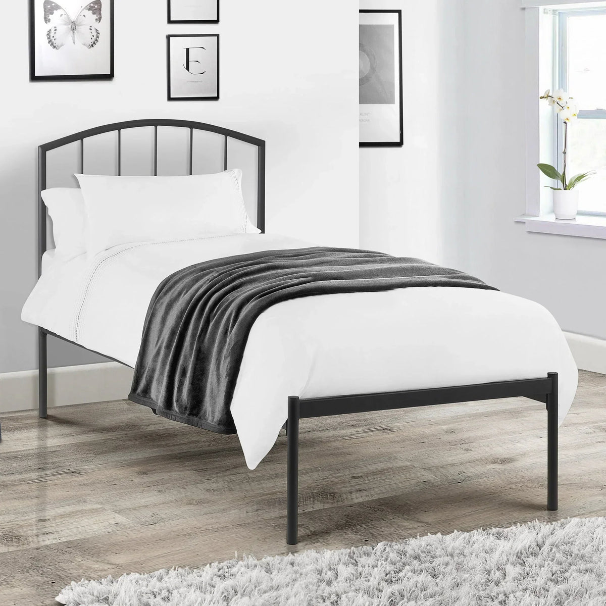 Single size metal bed frame with white bedding and grey throw in modern bedroom