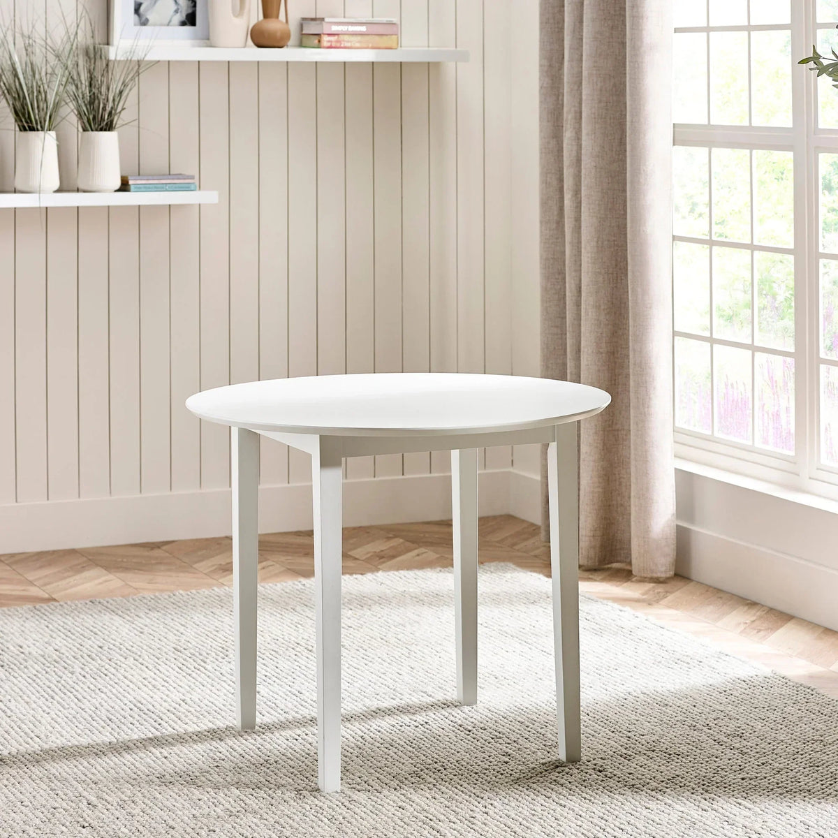White round dining table with four legs in bright modern living room