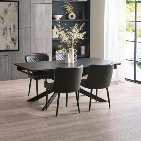 Black rectangular dining table with black leather chairs, light wood floor, modern room setting