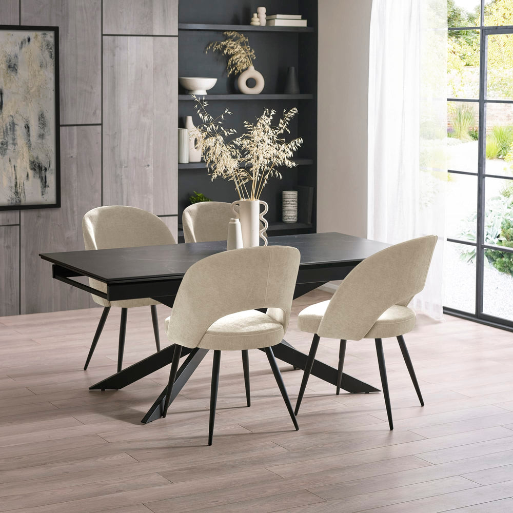 Close-up of black extending dining table with light beige fabric chairs on light wood floor
