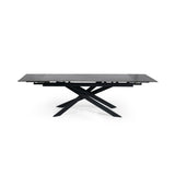 Extended rectangular dining table with black marble top and black metal crossed legs, front view isolated on white
