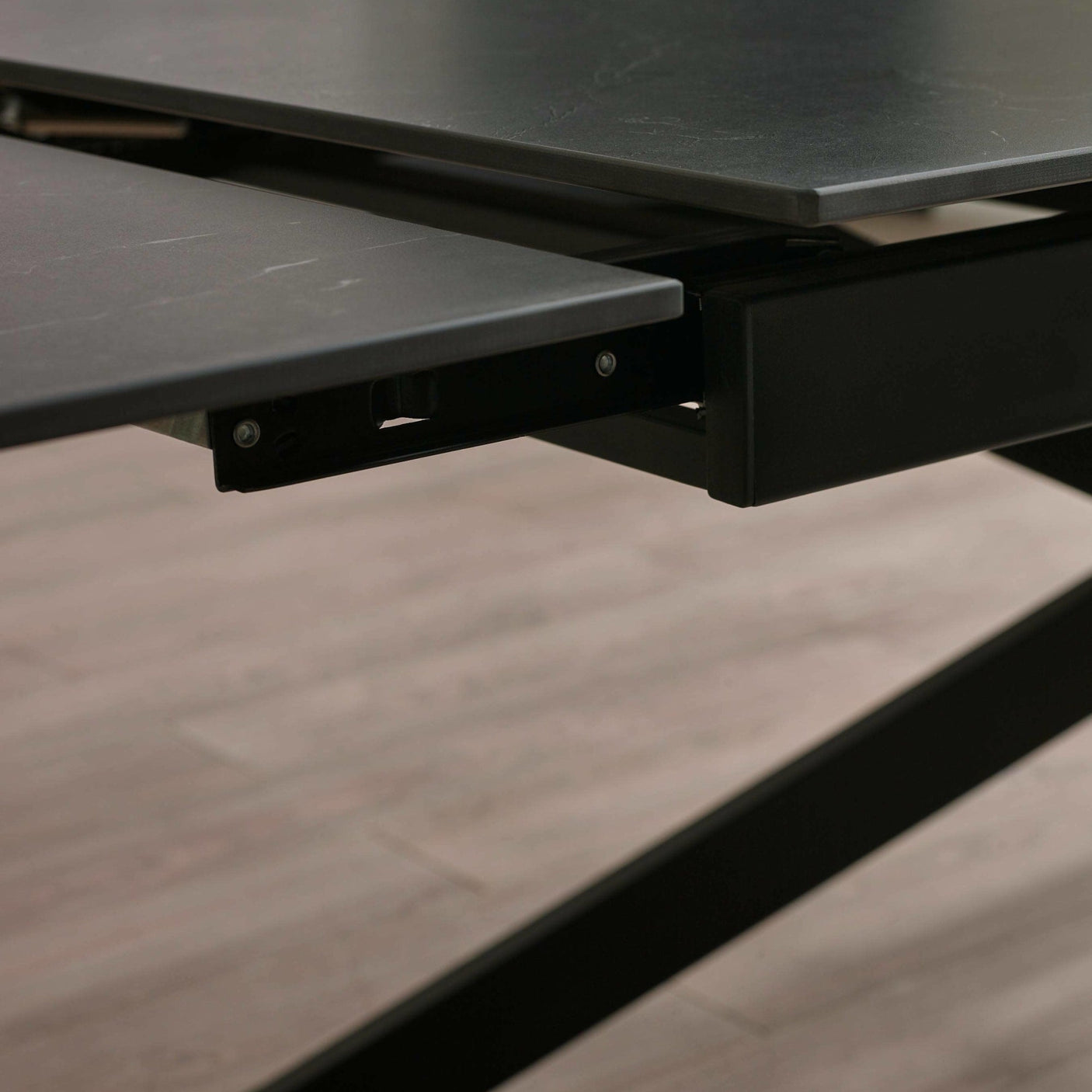 Close-up of black marble tabletop edge and metal frame mechanism for extending the table