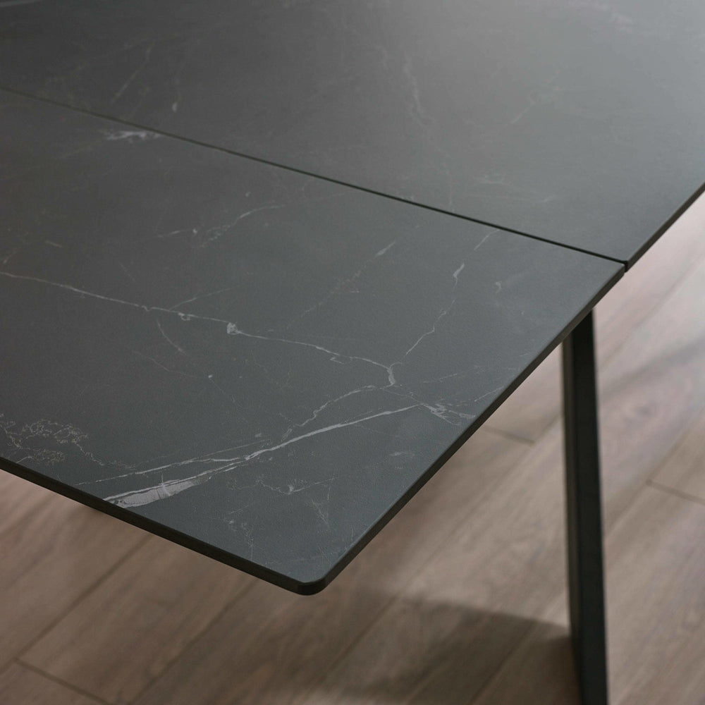 Close-up of corner of black marble tabletop with subtle veining and laminate detail on wooden floor