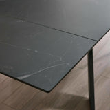 Close-up of corner of black marble tabletop with subtle veining and laminate detail on wooden floor