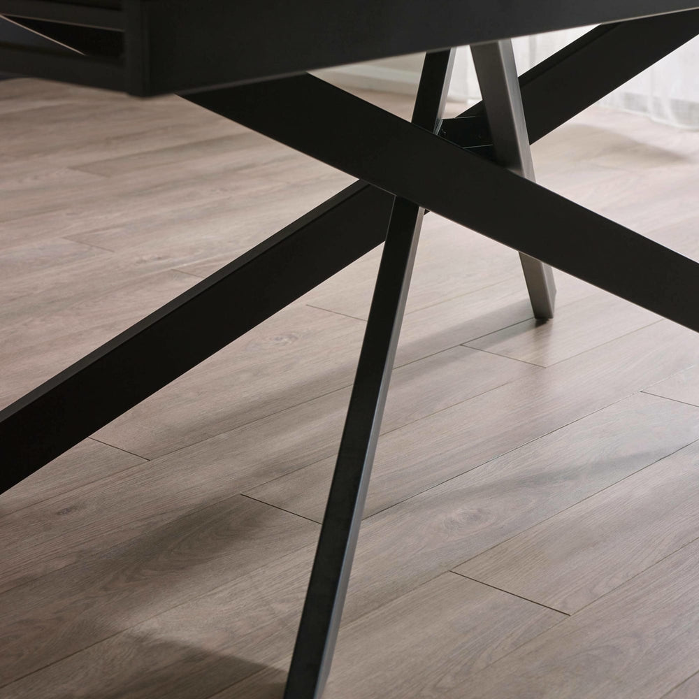 Close-up of black metal crossed legs supporting the table on light wooden floor