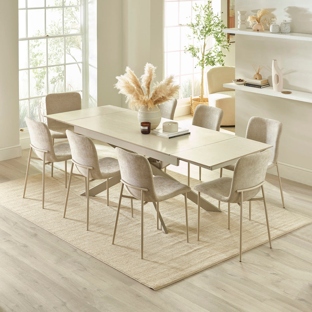 Extended light beige dining table with six chairs in bright room viewed from slightly elevated angle