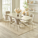 Extended light beige dining table with six chairs in bright room viewed from slightly elevated angle