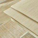 Close-up of cream crossed metal legs supporting light beige extending dining table on textured beige rug