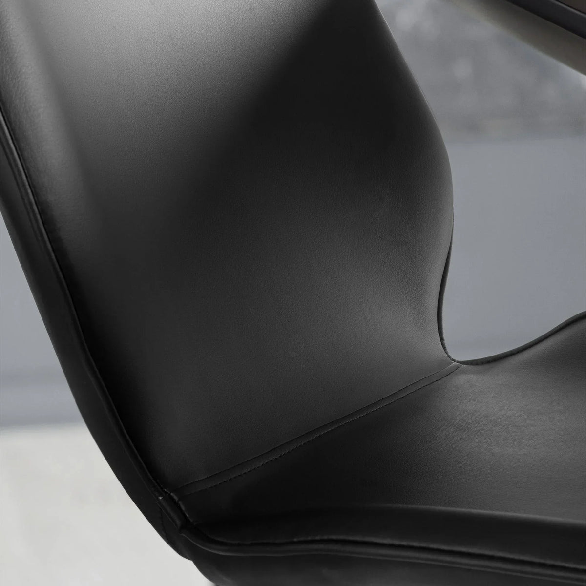 Close-up of black dining chair seat and curved backrest with smooth faux leather upholstery