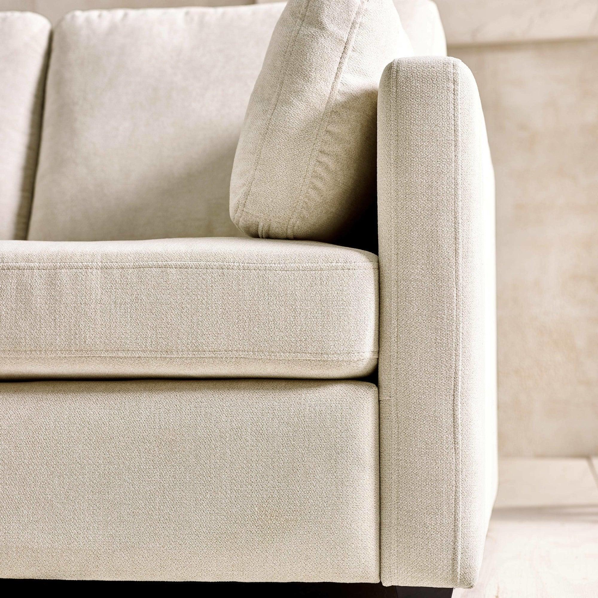 Beige fabric sofa close-up showing cushion, armrest, and textured upholstery
