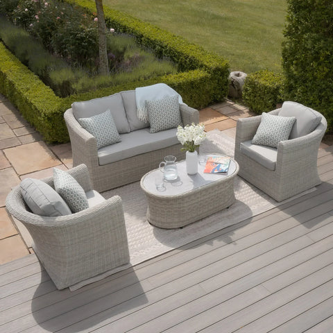 Light grey rattan garden furniture set with cushions and oval coffee table on patio decking