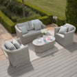Light grey rattan garden furniture set with cushions and oval coffee table on patio decking