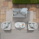 Grey rattan garden furniture set with sofa, two armchairs, and oval coffee table on patio