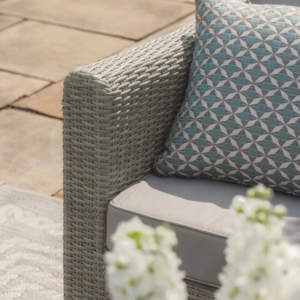 Grey rattan outdoor sofa arm with geometric cushion and grey seat cushion on patio