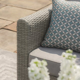 Grey rattan outdoor sofa arm with geometric cushion and grey seat cushion on patio