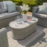 Grey rattan outdoor coffee table with glass jug, white vase, and magazine on patio