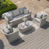 Rattan garden furniture set with grey cushions, armchairs, and coffee table on patio decking