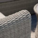Light grey rattan garden sofa armrest with woven texture and outdoor setting