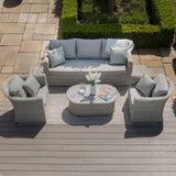 Light grey rattan garden sofa set with two armchairs and coffee table on patio decking