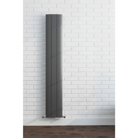 Tall vertical radiator against a white brick wall