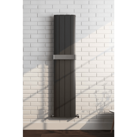 Vertical black radiator on a white brick wall