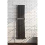 Vertical black radiator on a white brick wall