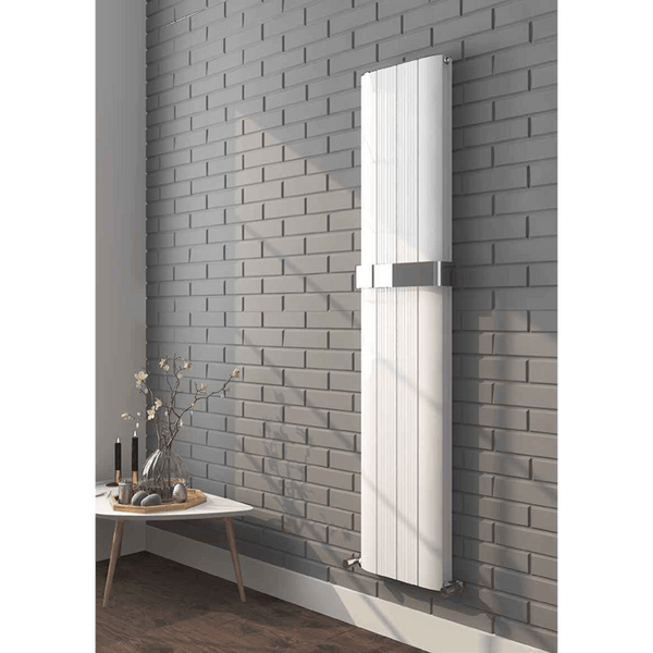 White radiator mounted on a gray brick wall with a small table and decorative items below.