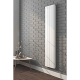 White vertical radiator on a gray brick wall with a small table and decorative items below.