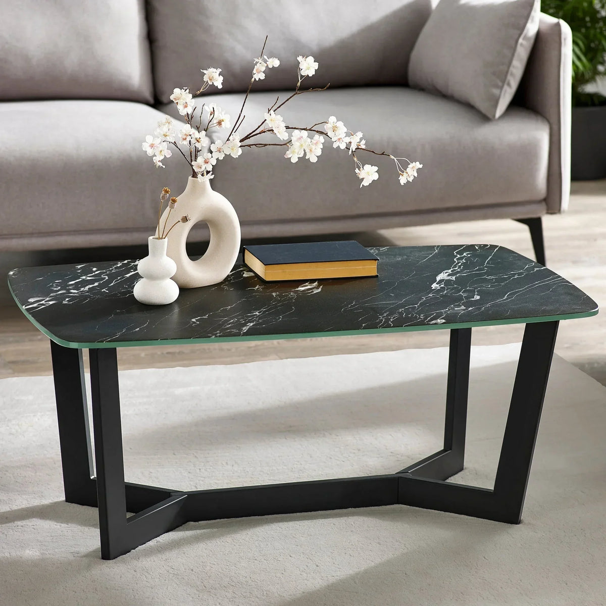 Black marble coffee table with modern metal legs, decorative vases and book in living room