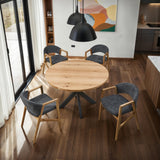Round oak dining table with four grey upholstered chairs in modern kitchen setting