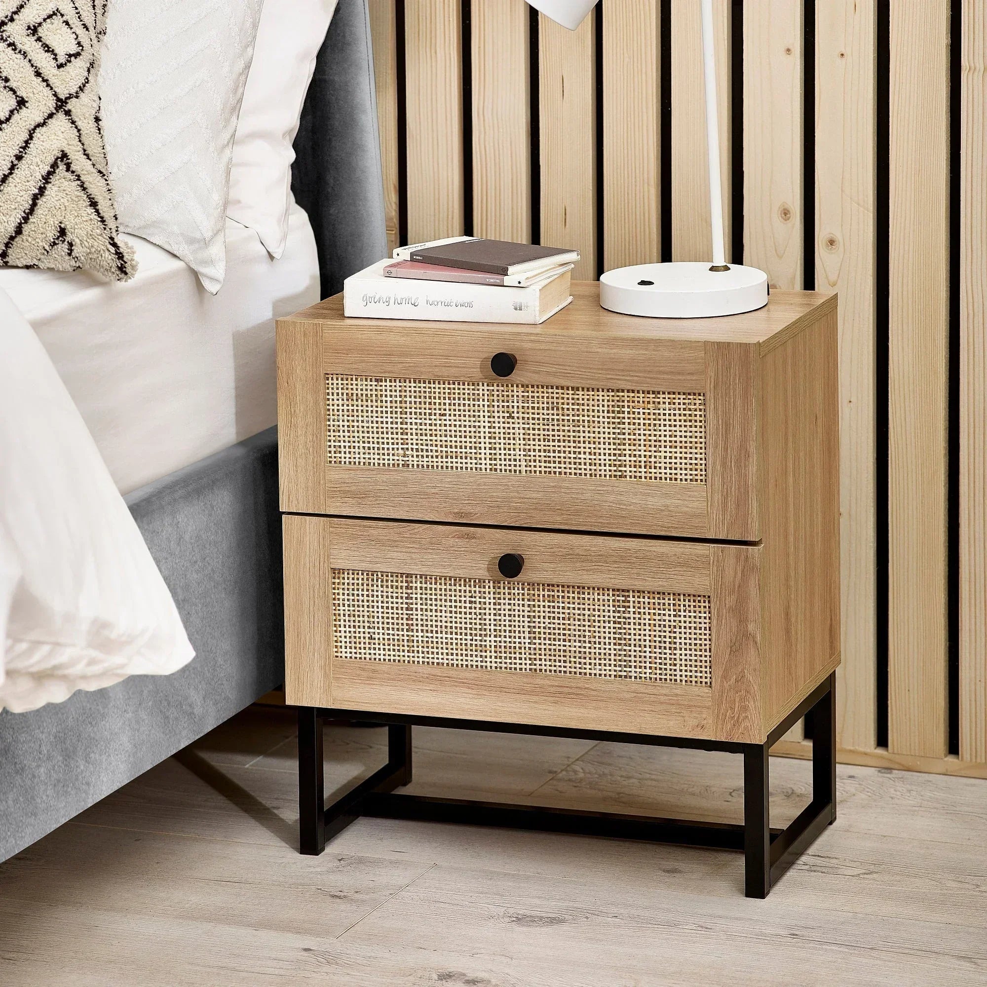 Oak bedside table with two drawers, rattan fronts, black legs beside bed