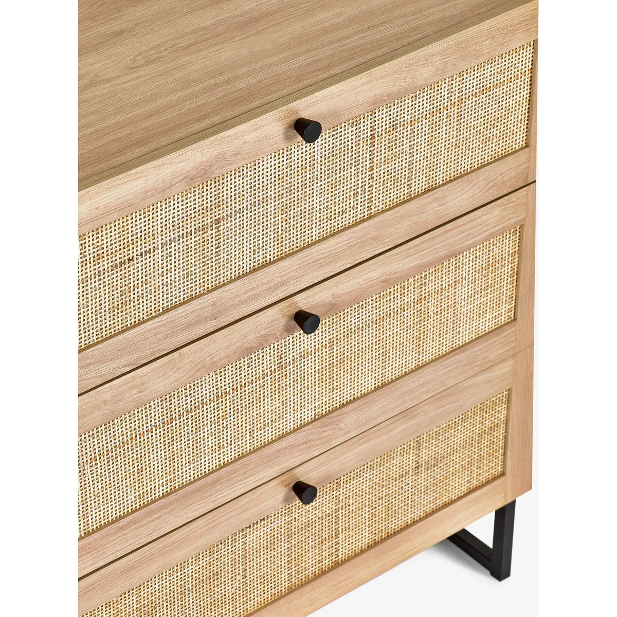 Oak three drawer chest with rattan fronts and black metal handles, close-up angle