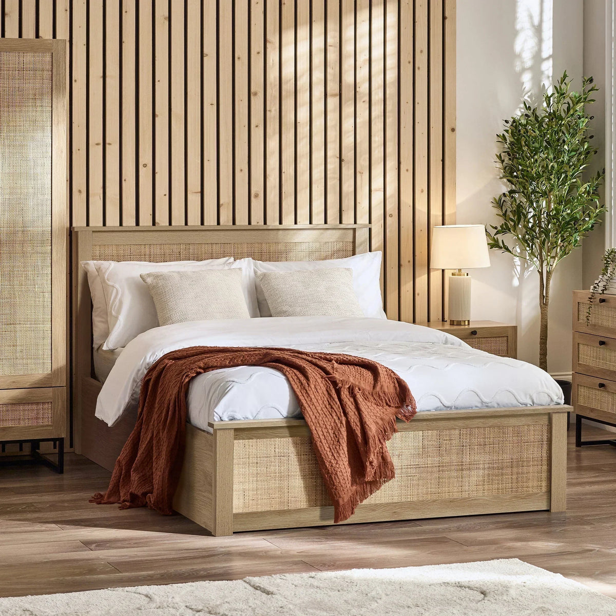 Oak rattan double ottoman bed with white bedding and throw in a modern bedroom
