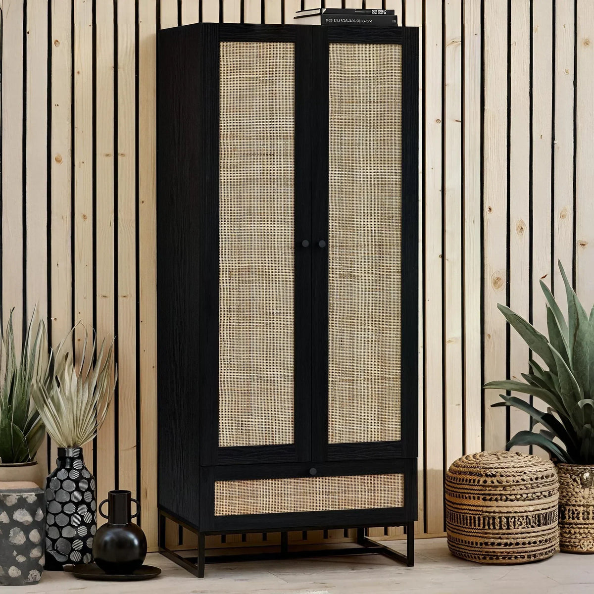 Black wardrobe with woven rattan doors and drawer set against slatted wooden wall, modern decor