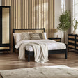 Black rattan double bed with natural woven headboard in modern bedroom setting