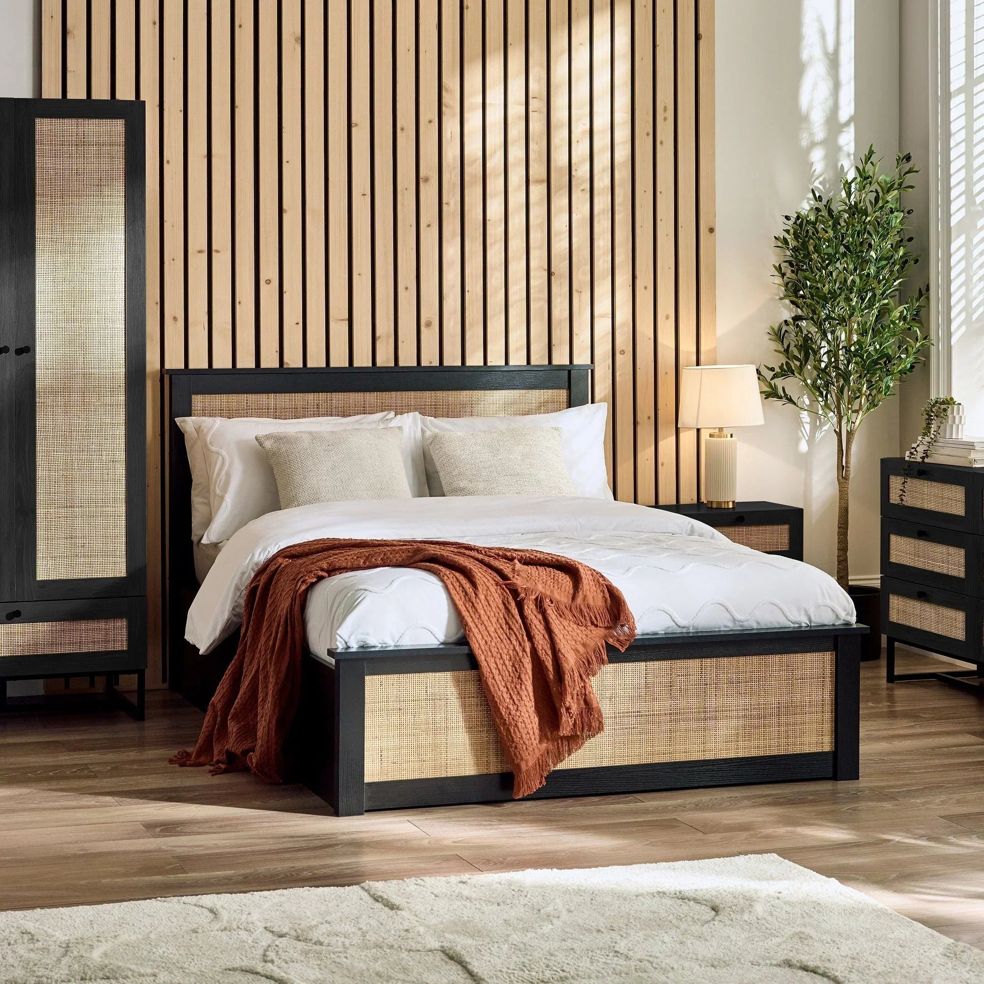 Black rattan ottoman bed with natural woven panels in modern bedroom setting