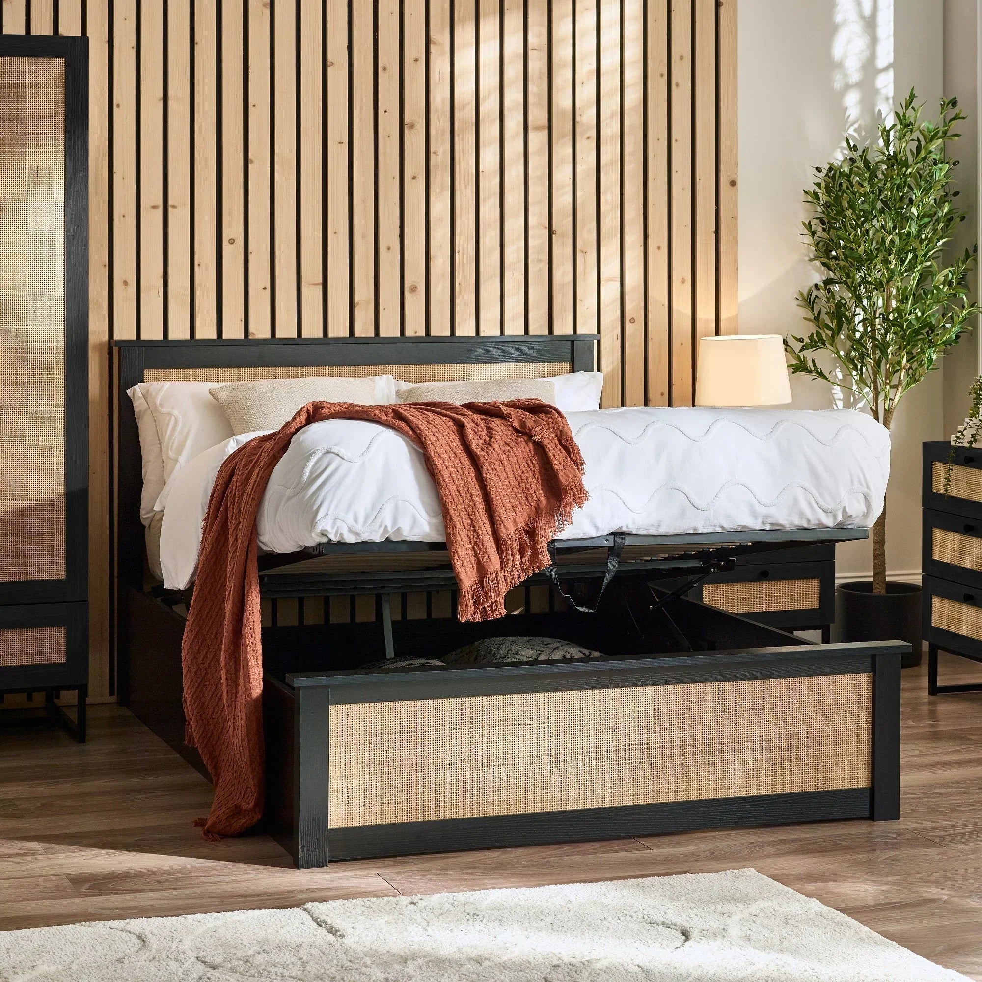 Black rattan ottoman storage bed with lift-up base in modern bedroom setting