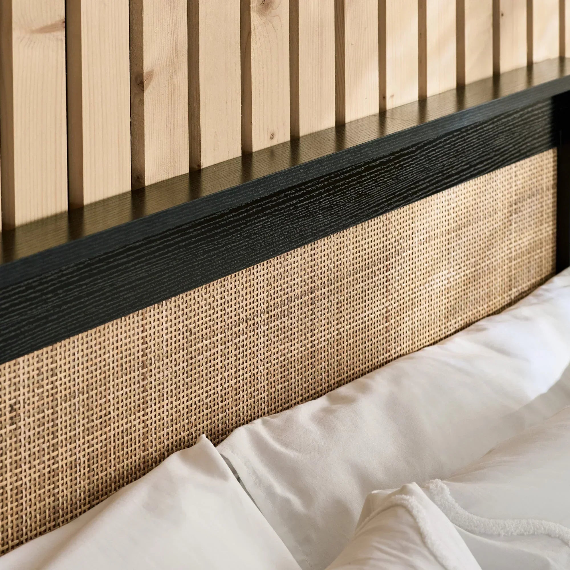 Black rattan ottoman detail with woven panel and textured wood headboard accent