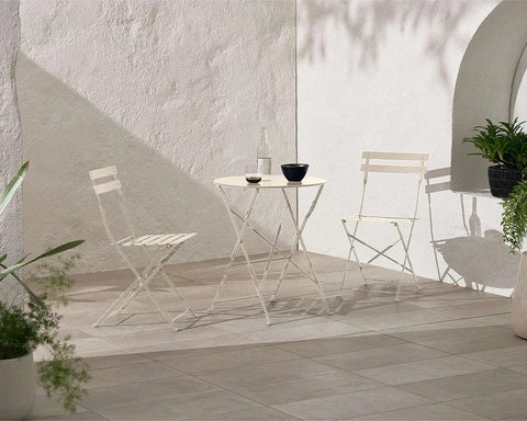 Champagne metal bistro set with two folding chairs and round table on a tiled patio