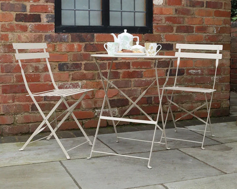 Champagne metal bistro set with foldable table and chairs in courtyard setting