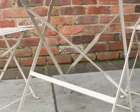 Champagne metal bistro chair legs and crossbars on patio against brick wall