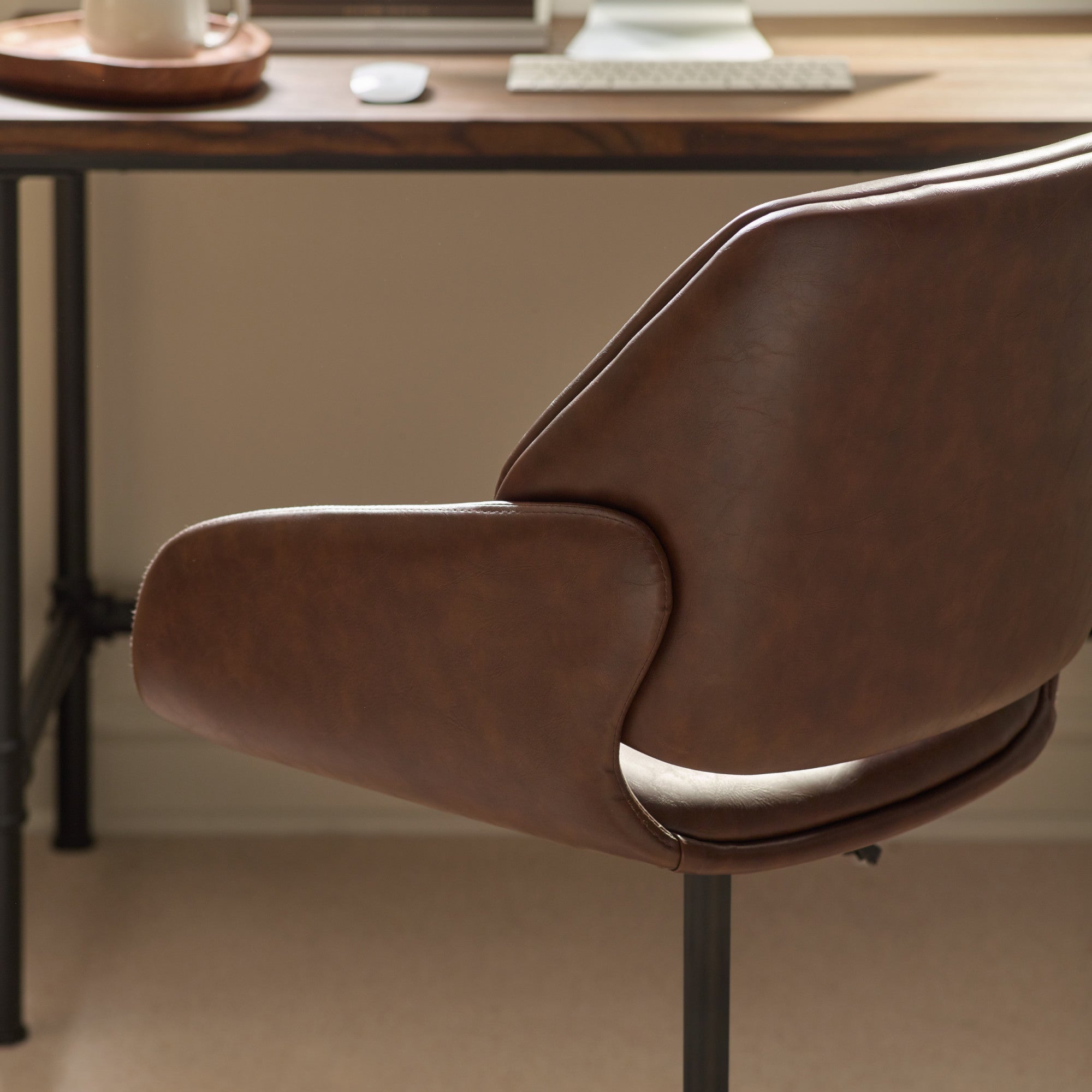 Close-up of brown swivel office chair angled seat and curved armrest in home office