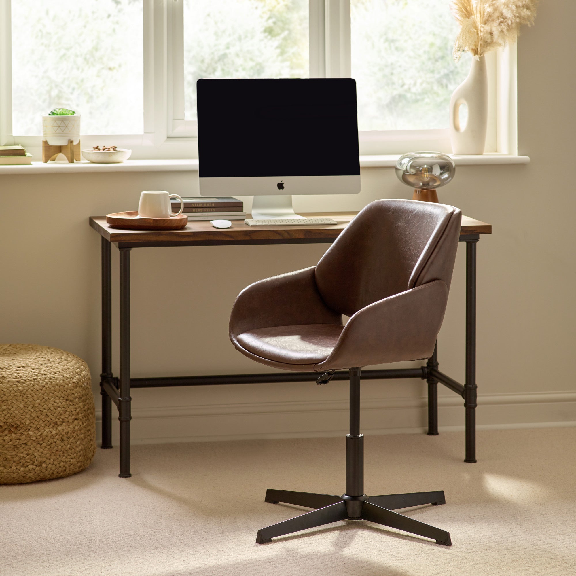 Brown leather swivel office chair with black star base in a home office setting by a wooden desk