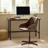 Brown leather swivel office chair with black star base in a home office setting by a wooden desk