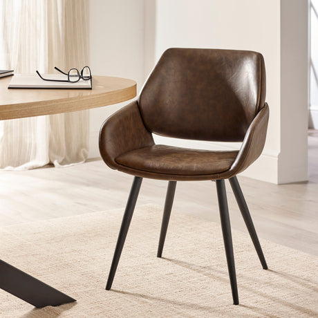 Brown upholstered dining chair with tapered black metal legs beside light wood round table in neutral room.