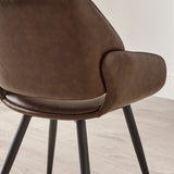 Close-up of brown upholstered chair back and armrest with black angled legs on wooden floor