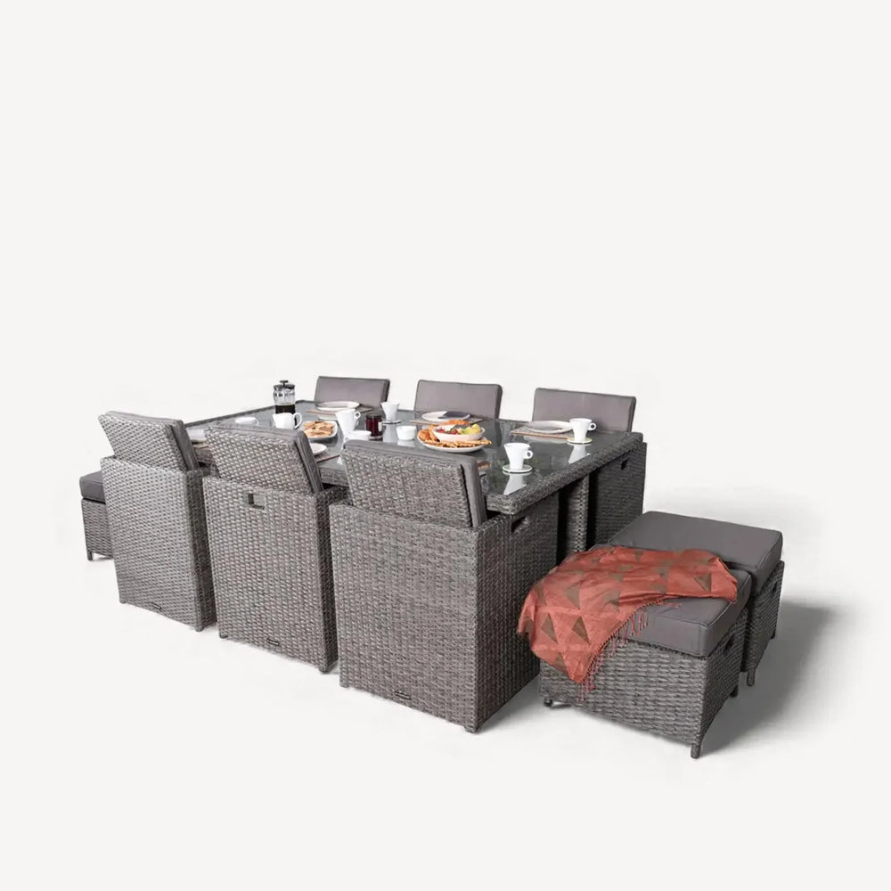 Grey rattan outdoor dining set with chairs, stools, glass table and place settings